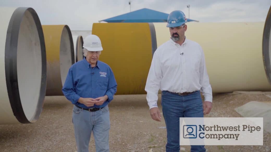 John Holden and Eric Stokes walking amongst large diameter steel pipe